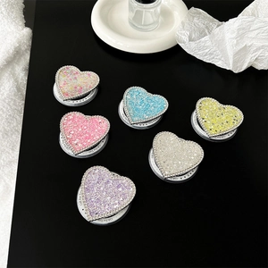 Supporto per telefono a cuore con strass e paillettes colorate su sfondo nero opaco