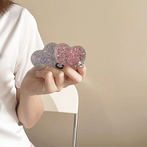 Close-up of three glittery heart phone grips in purple, pink, and silver sequins