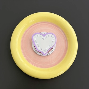 Detail view of pink heart MagSafe phone grip on a round ceramic vanity display tray