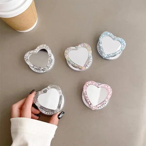 Detail showing five glitter heart-shaped MagSafe grips with built-in mirrors on a table