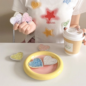 Close-up of heart-shaped glitter phone grips in five colors with silver beaded edges