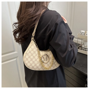 Close-up of beige half-moon underarm bag with repeat M pattern and gold chain strap
