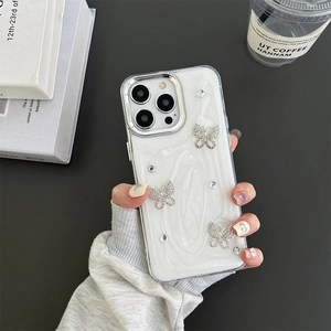 Macro detail of luxury silver rhinestone butterflies on white iPhone case with glitter