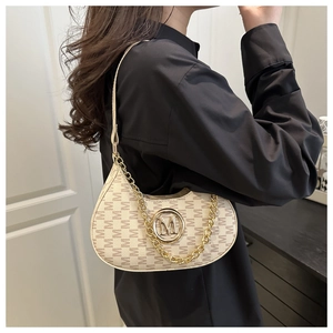 Detailed shot of beige monogram hobo bag with gold M logo and elegant metal chain strap