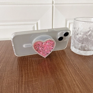 Detailed view of pink heart-shaped glitter phone grip with rhinestones on clear case