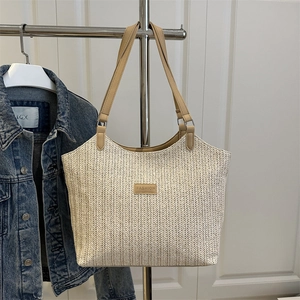 Retro woven straw tote bag with brown leather handles and fashion logo in lifestyle setting