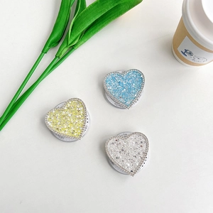 Dettaglio di supporti per telefono a cuore con glitter e strass in giallo blu argento