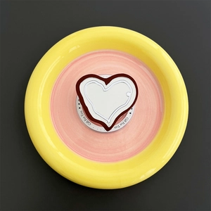Close-up of heart-shaped magnetic phone grip and mirror on colorful ceramic tray
