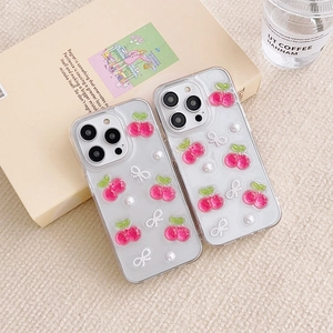Detail of transparent iPhone case featuring 3D cherry charms and pearl bow accessories