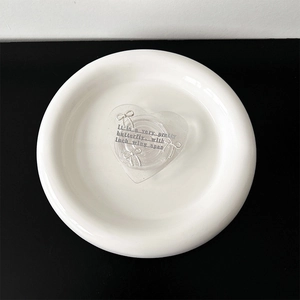 Detail of a transparent heart phone grip with a silver bow and artistic English text
