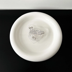Close-up of heart phone grip with silver bows and text on white ceramic plate