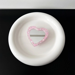 Macro detail of heart-shaped pink glitter phone socket with a mini makeup mirror center
