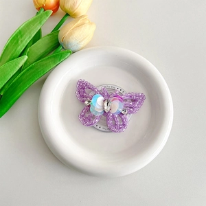 Detail of a purple beaded butterfly with rhinestones and sequins on a white display tray