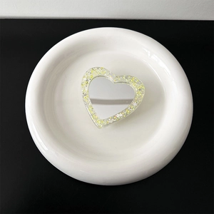 Detail shot of heart-shaped glitter phone grip with a built-in makeup mirror on white tray