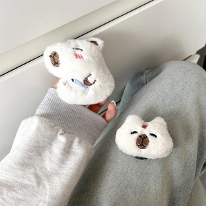 Detail of plush capybara phone grip featuring fine embroidery of small fish and strawberry