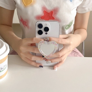 Detail of glitter heart magnetic phone grip with mirror shown on a white smartphone
