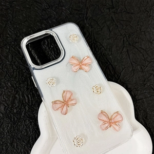 Détail de papillons roses et fleurs perlées sur coque iPhone avec cadre en métal argent