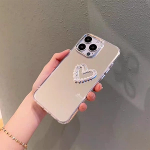Gros plan d'une coque miroir pour iPhone ornée d'un double cœur en perles et strass