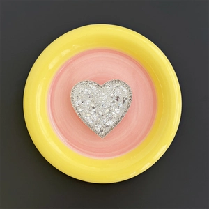 Macro detail of heart-shaped phone grip with glittering white rhinestones on pink tray