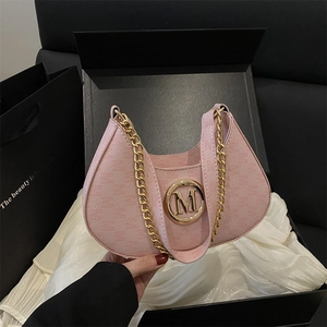 Pink crescent underarm bag with gold M buckle and chain strap on black gift box
