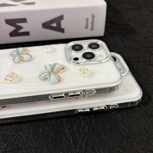 Détail de coque iPhone 15 Pro Max avec papillons 3D et motifs floraux scintillants