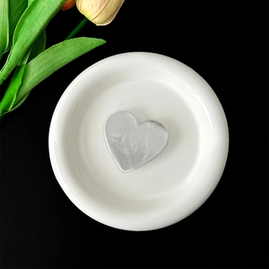 Close-up of heart-shaped glitter phone grip with metallic texture on white ceramic plate