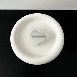 Silver heart-shaped mirror grip with fine brushed texture on a white ceramic plate