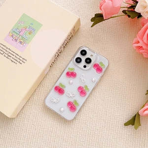 Detail of clear iPhone case with 3D pink cherries and pearl bow on cream background