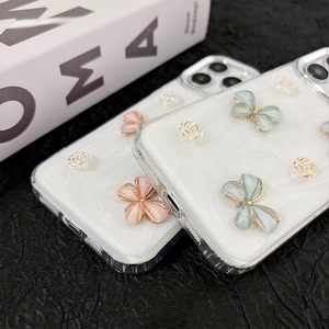 Détail de papillons 3D et fleurs en résine sur une coque iPhone à paillettes avec texture marbre