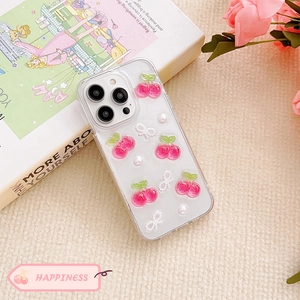 Detailed view of cherry and pearl bow charms on a clear protective iPhone case