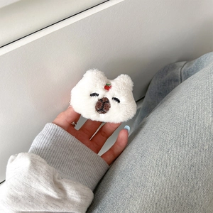 Close-up of white plush bear phone grip with strawberry embroidery held by hand