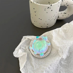 Detail of holographic turtle phone grip with iridescent finish and gift text on base