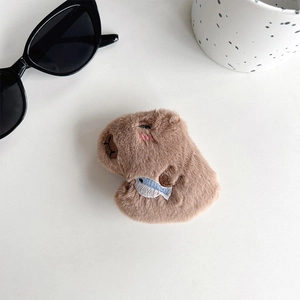 Close-up of plush capybara phone grip featuring embroidery and a blue fish accessory