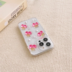 Close-up of clear iPhone case with resin pink cherries and pearl bow on woven surface