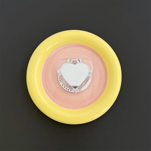 Detail shot of heart-shaped Magsafe phone mirror holder on a decorative ceramic dish
