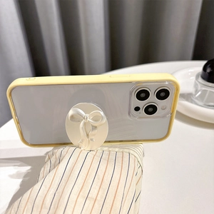 Detail of cream yellow iPhone case featuring a white 3D bow phone socket grip with gift text