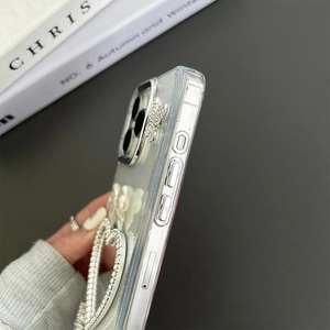 Detailed close-up of a clear iPhone case featuring rhinestone hearts and a 3D resin bow