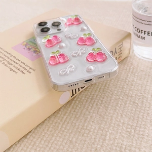 Detail of iPhone case with 3D pink cherry, pearls and white bow tie on cream book