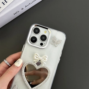 Detail of glitter iPhone case with rhinestone butterfly, white bow and heart mirror