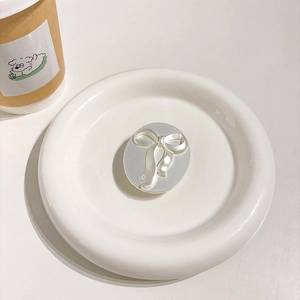 Detail view of a 3D silver bow phone socket holder with glossy finish on ceramic plate