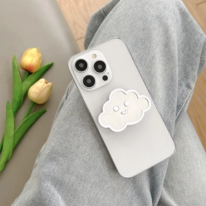 Close-up of a cute white cloud-shaped phone grip on a phone held against denim jeans