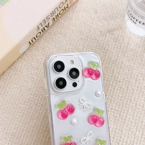 Detail of iPhone case featuring 3D pink cherry and white pearl bow on transparent back
