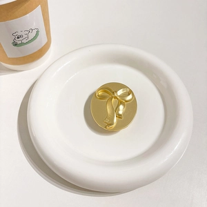 Detailed top view of a gold oval bow phone grip holder on a white ceramic plate