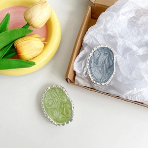 Detailed view of irregular metal badge pins in morandi green and grey blue colors