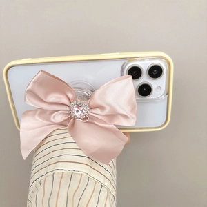 Close-up of pink satin bow phone socket with heart gemstone on a clear phone case