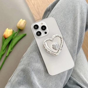 Close-up of a silver heart-shaped phone grip with a rose design on a white smartphone.