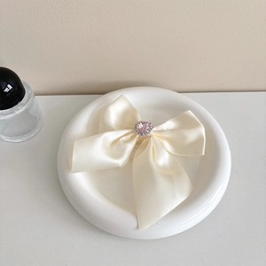 Macro shot of cream satin bow phone holder with pink heart crystal and rhinestones
