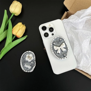Detail of marble pattern phone grip with white bow and Lucky flower rhinestone decor