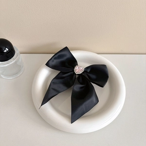 Macro shot of black satin bow with pink heart gemstone and sparkling rhinestones