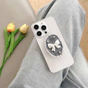 Sparkling rhinestone bow flower phone socket grip on white iPhone with tulip background
